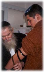 הרב יצחק זילבר מניח תפילין לאחד ממשתתפי תוכניות תולדות ישורון